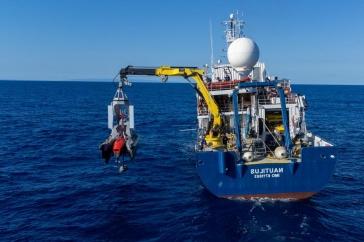 鹦鹉螺号探测船尾部，一台起重机将DriX自主水面船部署到海洋中.