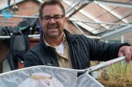 主要研究 researcher Michael Chambers with a greenhouse-grown shrimp in a net