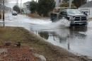 Two vehicles drive through flooded road conditions.